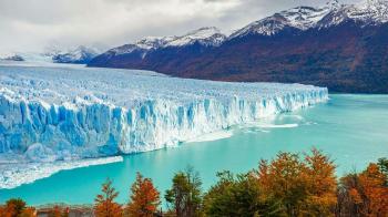 Fondo de pantalla de Majestuoso glaciar azul frente a montañas nevadas y lago turquesa